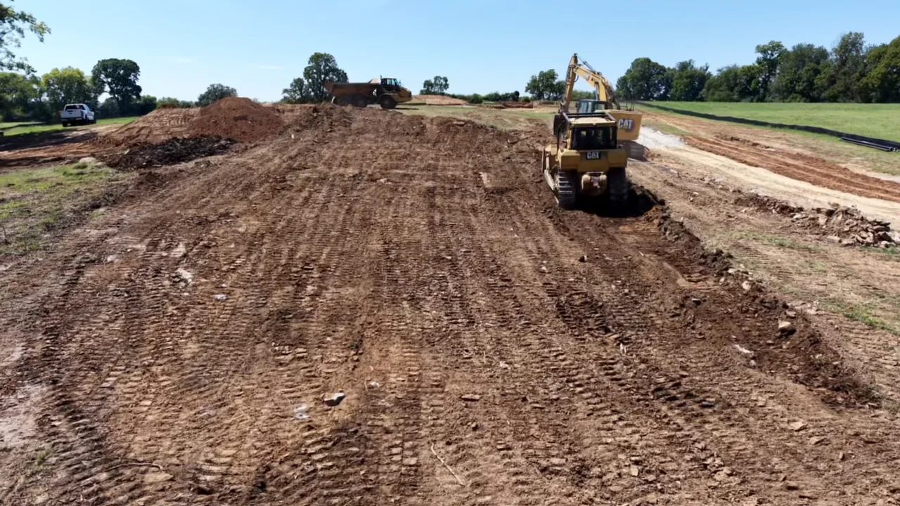 Excavator and load truck working in a graded area.
